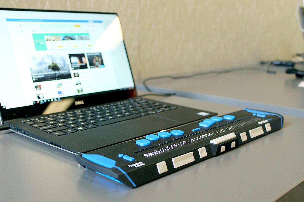 A laptop connected to a refreshable braille display, representing web accessibility and inclusive design for visually impaired users.