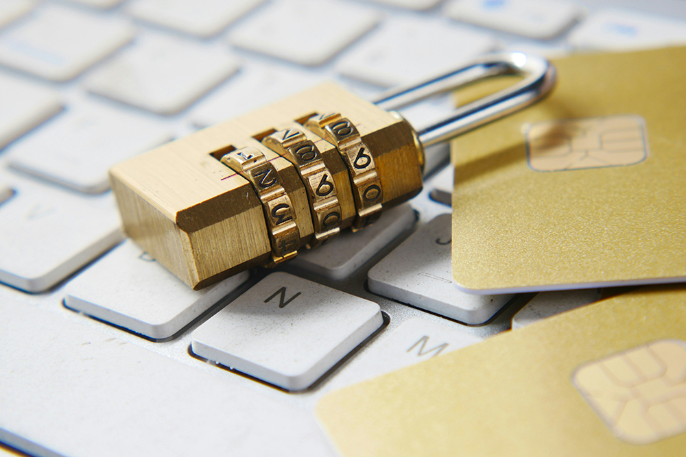 A combination padlock placed on a computer keyboard alongside credit cards, symbolizing website security and data protection.