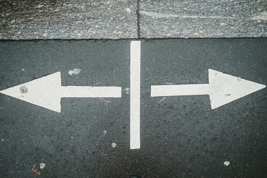 Two arrows painted on pavement pointing in opposite directions, symbolizing choosing between different website platforms.