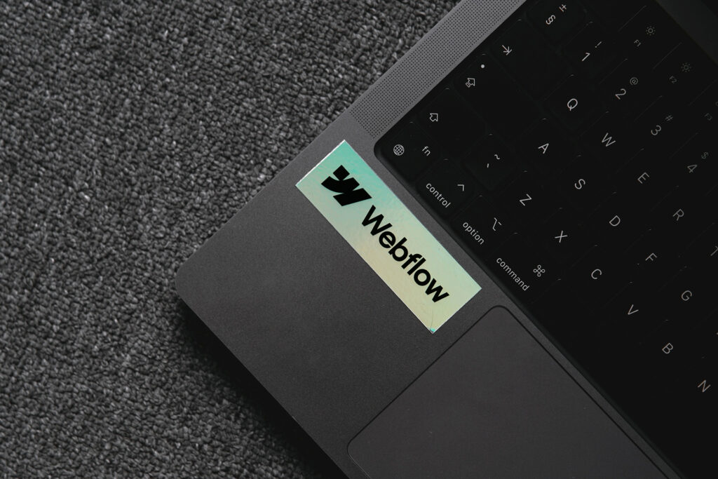 Close-up of a laptop with a Webflow sticker, representing the Webflow website builder platform.